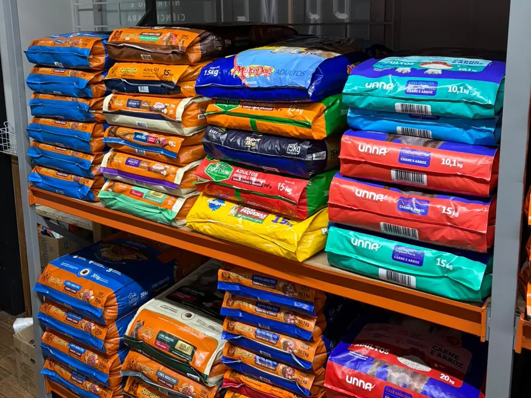 Prateleira industrial da loja cheia de sacos grandes de ração empilhados — Special Dog, Special Cat, Unna, MultiDog, Dog Chow e Pedigree — nos pesos de 10,1, 15 e 20 quilos
